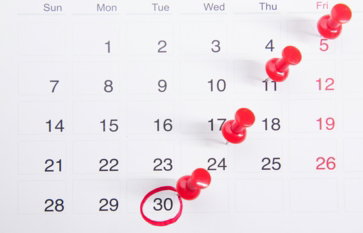 a calendar with red push buttons pinned to it